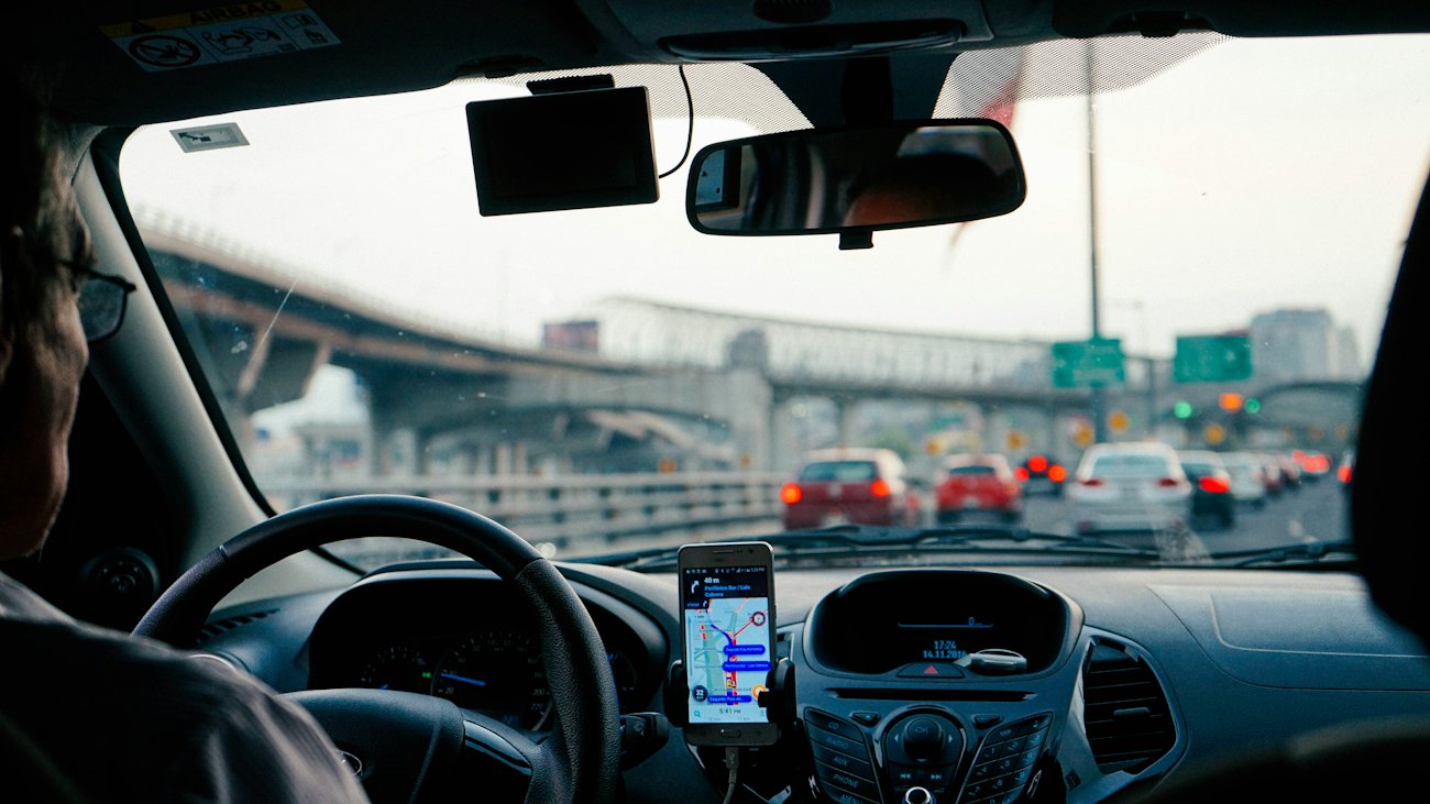 Motorista dirigindo com o celular no painel mostrando o mapa